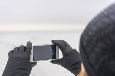 Kadın telefonu kış manzara üzerinde fotoğraf çekmek