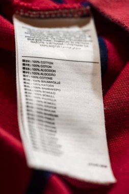İçinde kırmızı pamuklu gömlek üzerinde etiket. Birçok dilde metin % 100 pamuk.
