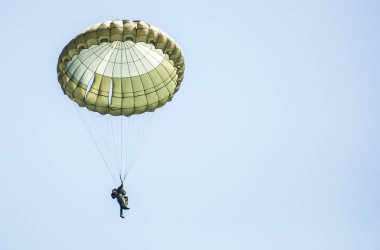 Paraşütçü askeri tatbikat sırasında bir askeri uçaktan atlamak. Gökyüzünde paraşüt ile pek çok asker.