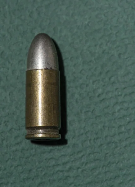 一个干净背景上的武器弹药筒 绿色背景上的单个孤立的子弹 — 图库照片