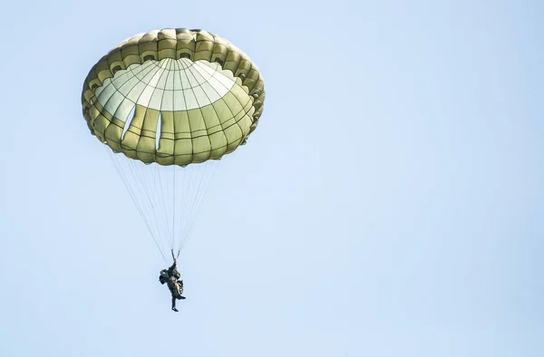 Paraşütçü askeri tatbikat sırasında bir askeri uçaktan atlamak. Gökyüzünde paraşüt ile pek çok asker.