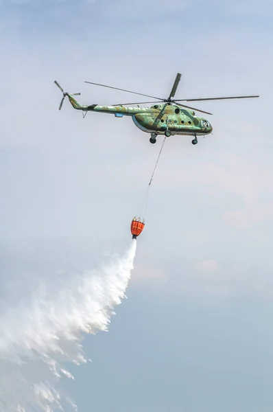 Su taşıma yeşil yangın söndürme helikopteri. Helikopter yangınları söndürür. 