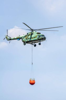 Su taşıma yeşil yangın söndürme helikopteri. Helikopter yangınları söndürür. 