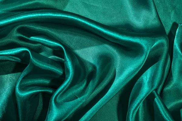 Yeşil saten kumaş arka plan. Parlak yeşilimsi ipek zemin. 
