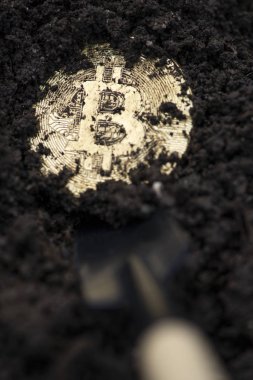 Topraktaki Bitcoin para. Araştırma cryptocurrencies kavramı. Sarı gömülü sikke ve kürek.