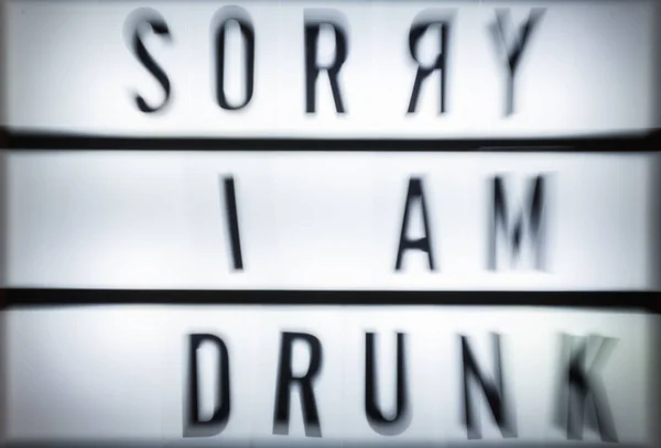 Message Sorry I Am Drunk on illuminated board. Drinking alcohol concept with text. Daylight from window. Room interior. Black letters I Am Drunk on white wallpaper wall.