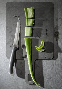 Aloe vera dilimleri karanlık gemide. Sağlık ve güzellik kavramı. Closeup aloe yaprak backlight üstünde kesmek..