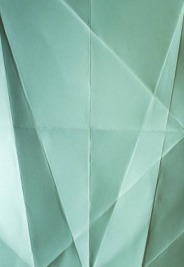 Yeşil renk kağıt katlanmış. Pastel tonları. Sert doğal ışık. Kıvrımlar ve kırışıklıkları kağıt üzerinde. Geometrik şekiller ve kağıt üzerinde rakamlar.