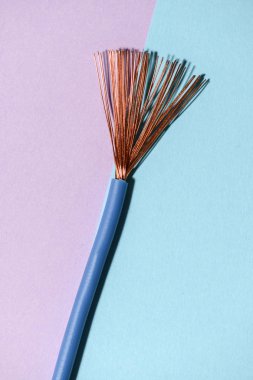 Pembe ve mavi arka plan üzerinde elektrik kablosu. Bakır teller yayılır. Minimalist elektrik arka plan.