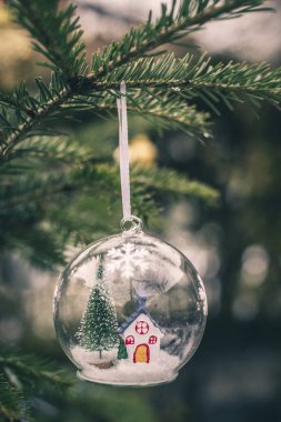 İçinde Noel ağacı ve ev olan şeffaf bir kristal top.. 