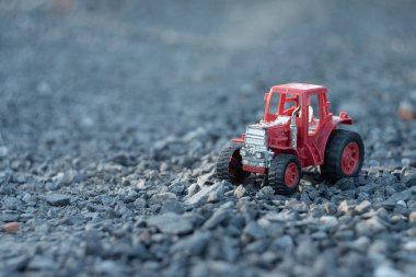 Kayalık zeminde kırmızı oyuncak traktör ayakta. O fotoğrafı arka plan olabilir