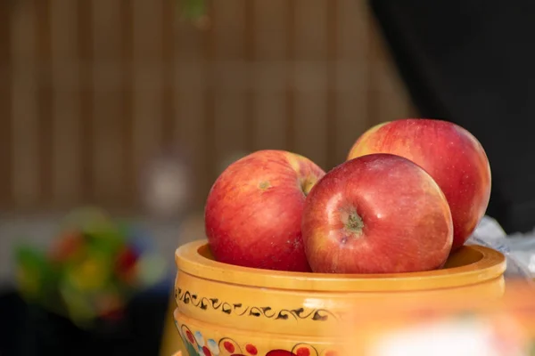 Three apples stacked in a clay pot with ethnic ornaments. Vintage autumn gardens. Symbol of healthy eating