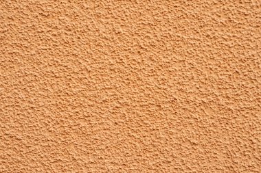 Evin duvarının bir parçası. Bej kum rengi alçısı. Tanecikli yüzey