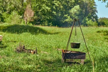 Ormanda yemek pişirmek. Yakacak odunlu metal ızgara. Tabakla kase.
