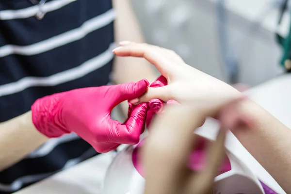 Manicure master makes manicure for a girl, smears his nails