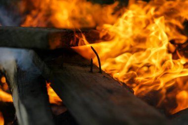 Eski evin bir kısmı alevlerin parlak dilleriyle kaplı. Ocağın fotoğrafı.