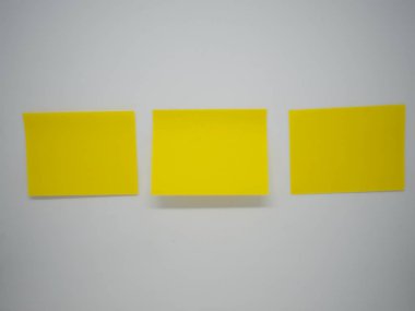 Üç sarı yapışkan notu sopa yatay duvardaki beyaz izole