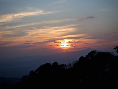 Eveing günbatımı içinde belgili tanımlık bulut ağaç siluet ve dağ, Nan, Thailand