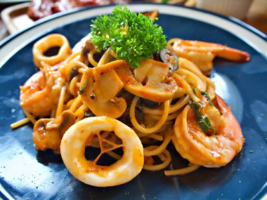Mavi plaka üzerinde kalamar, karides ve mantar ile deniz ürünleri spagetti