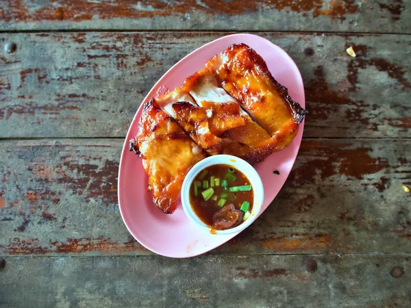 Ahşap masaya yerleştirilen tabakta sos lu Tay tarzı ızgara tavuk üst atış