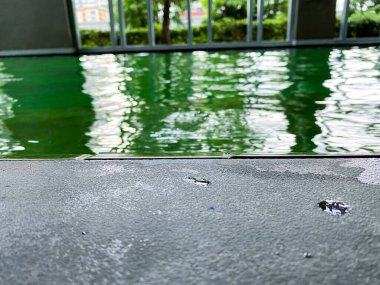 Yüzme havuzunun kenarı, yeşil su arka planı ve su damlası.