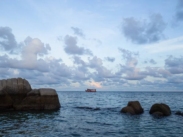 The sea rock near the beach and the boat at the middle of the sea in Koh Tao, Thailand