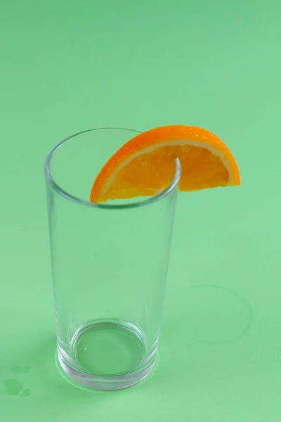 Порожнє Скло Апельсиновою Скибочкою Ізольовано Зеленому Фоні — стокове фото