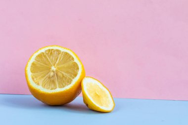 Minimalistic picture of half of lemon on the pink and light blue background with space for text