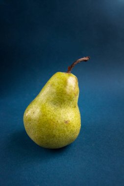 Olgun yeşil armudun üzerinde mavi arka plana karşı. Sıfır atık ve organik gıda konsepti