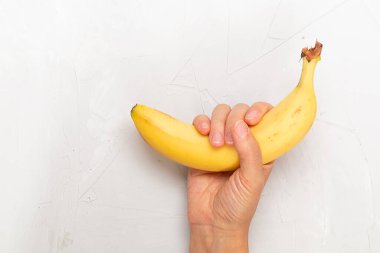 El açık gri arkaplan üzerinde sarı muz tutuyor, metin için boş boşluk