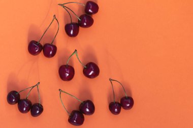 Turuncu zemin üzerinde kırmızı kirazlar ve boşluk