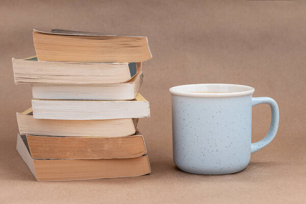 stack of old book with a cup of coffee or tea, beige background 