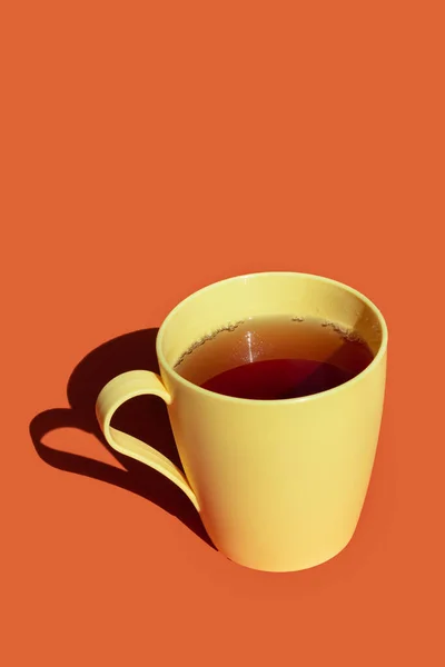 Gorąca Herbata Żółtym Plastikowym Kubku Pomarańczowym Tle Twarde Światło Głębokie — Zdjęcie stockowe