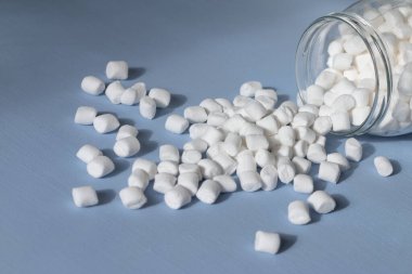 Açık mavi arkaplanda cam bir kavanozda şekerlemeler