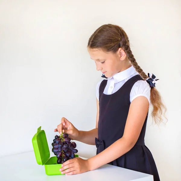 穿校服的女孩把葡萄放在饭盒里 在学校吃水果午餐 儿童健康食品 孩子们选择水果 已经做自己正在准备一个饭盒 — 图库照片