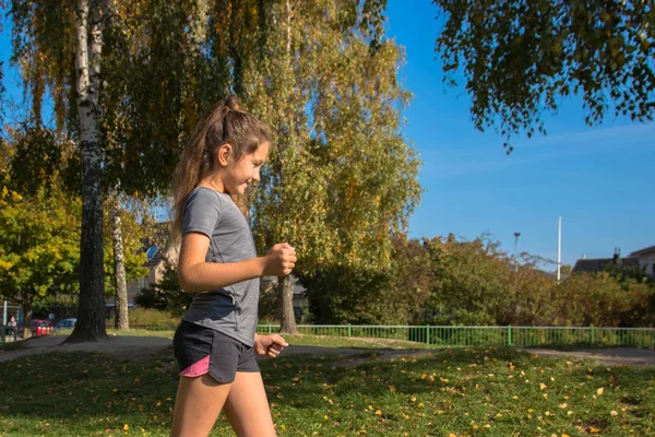 Happy teen girl runs on green grass. The girl loves to run and enjoys jogging. The teenager is happy. Healthy lifestyle children and teenagers concept.