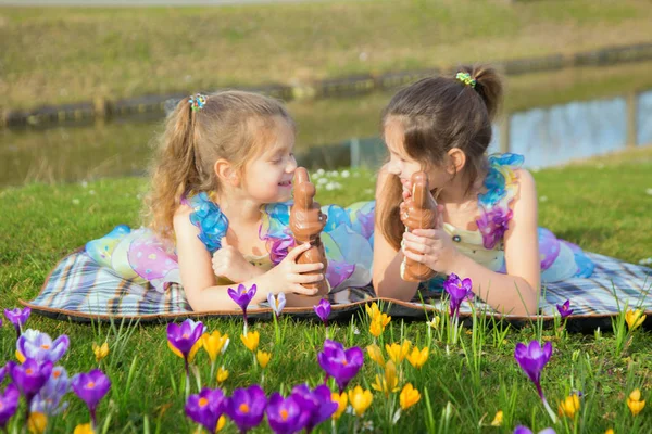 Two equally dressed little sisters lie among the flowers. — Stock Photo, Image