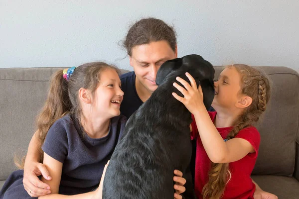孩子和狗拉布拉多亲吻他们的父亲 两个小女孩和一条狗抱着爸爸父亲节概念 — 图库照片