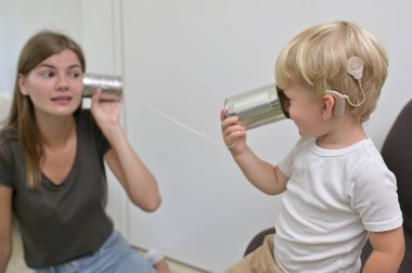 Koklear implantları olan teneke telefon çalan bir çocuk.