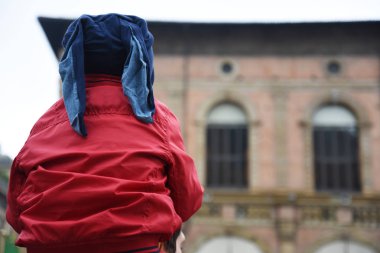 Kırmızı bir ceket ile bir çocuk babasının omuzlarında vardır. Bologna, İtalya