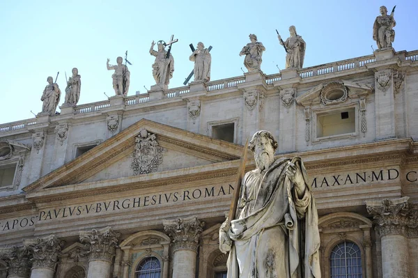 Statue of Apostle Paul in front of the St Peter\'s Basilica, Vatican City (Rome, Italy). Detail of the facade exterior on the blue sky background. Renaissance sculpture of the Apostle Paul with a sword in sunlight.