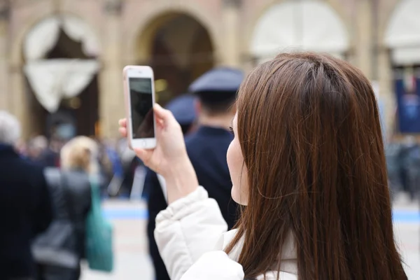 年轻女子在智能手机上拍照 在背景上 一个穿军装的人 意大利博洛尼亚 — 图库照片