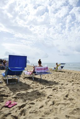 Kadınlar sahilde Dedikodu dergileri okuyarak rahatlatıcı. Sabaudia, Lazio, İtalya