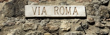 Mermer sokak tabelası Via Roma İtalya antik bir köyde. Arka plan bir taş duvar.
