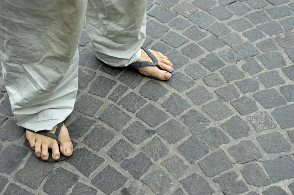 Kirli ayaklar giyen bir adamın eski taş zemine floplar flip. Bologna, İtalya
