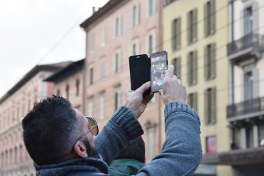 Hipster adam smartphone bir İtalyan sanat City ile fotoğraf çekmek. Bologna, İtalya