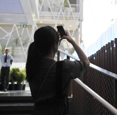 Asyalı Genç kadın uzun siyah saçlı bir fotoğraf ona telefon ile seyahate arka tarafında. Arka planda bir polis.