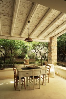 Beyaz ahşap masa ve sandalyeler yazlık evin arka bahçesinde ayarlayın. Yukarıda, beyaz ahşap bir çatı.