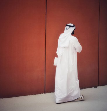 Güneş gözlüklü ve Arap elbiseli zarif bir adam ülkesinin sokaklarında yürüyor. Arap etnik kökeni kavramı.