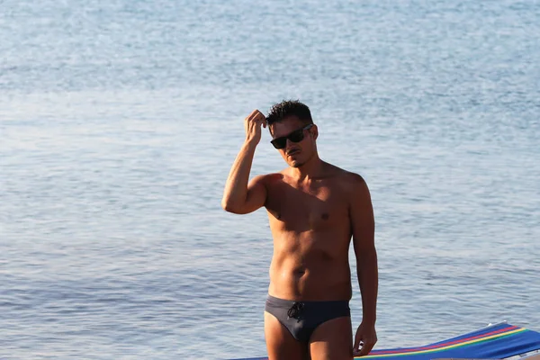 Przystojny Mężczyzna Okulary Przeciwsłoneczne Strój Kąpielowy Cieszą Się Plaży Zachodzie — Zdjęcie stockowe